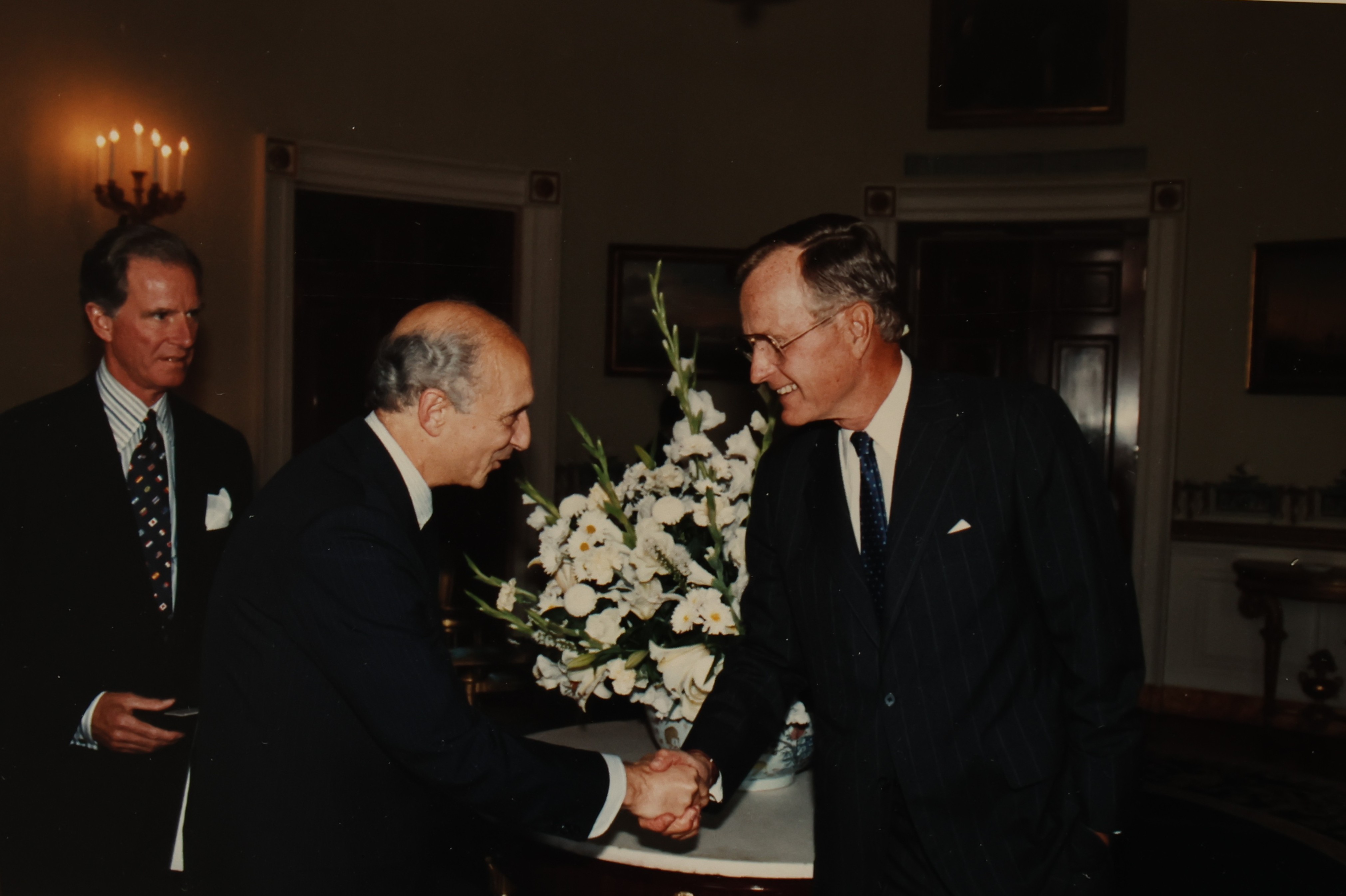 Foto que registra Rubens Ricupero, então embaixador brasileiro em Washington, encontrando e cumprimentando o presidente dos Estados Unidos George H. W. Bush. A foto foi feita na Casa Branca, por ocasião da cerimônia de apresentação das credenciais do embaixador Rubens Ricupero.